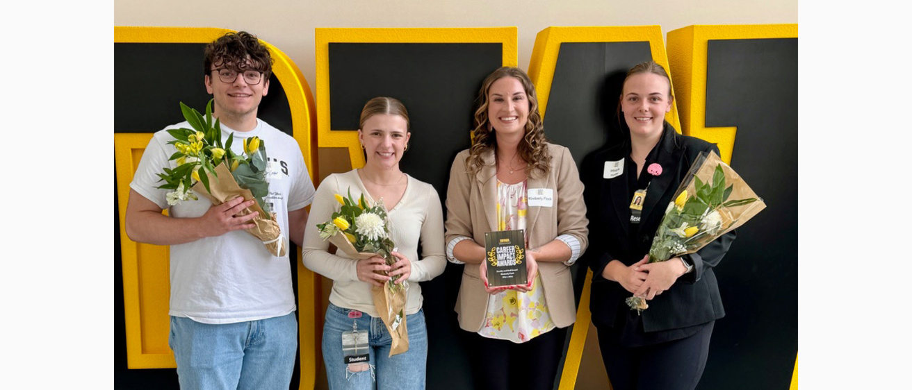 Four people standing in front of an IOWA logo
