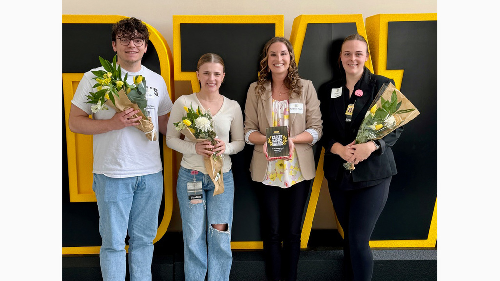 Four people standing in front of an IOWA logo