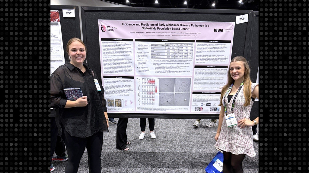 Two people standing in front of a research poster, smiling
